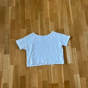 T-shirt - Vit t-shirt med detaljer. Storlek 12-14y men funkar bra som XS. T-shirten är lite kortare men lite bredare i passformen. Väldigt välanvänd har ett litet hål och mindre fläckar som enbart syns på nära håll.