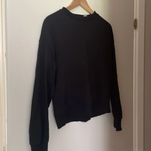 Svart tröja från H&M Divided - En enkel och stilren svart tröja från H&M Divided. Tröjan har långa ärmar och en normal passform, perfekt för vardagsbruk.