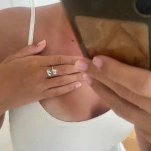 silvrig ring  - silvrig ring i rostfritt stål vilket gör den vattentålig och tappar inte färg! händer som kramar om fingret, storlek 17!