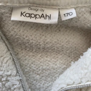 Grå fleece tröja från KappAhl - En mjuk och bekväm grå fleece tröja från KappAhl. Tröjan har en halv dragkedja framtill och långa ärmar. Perfekt för kyliga dagar.