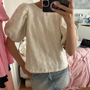 Topp med knyte i ryggen  - Topp med puffärmar och knye i ryggen. 
