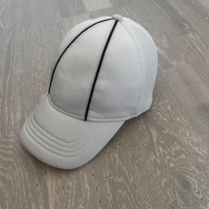Vit keps  - Denna keps är justerbar som anpassar storleken på huvudet och gör att den sitter bekvämt på huvet. 
