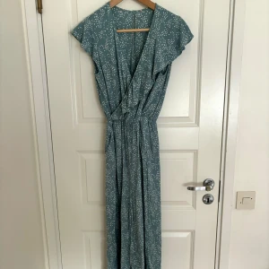 Jumpsuit - Detta är en grön- och vitfärgad jumpsuit. Jag vet tyvärr inte var den är köpt. Då jag har vuxit ur den väljer jag att sälja den. Den har två fickor på vardera sida av kroppen (se bilder). Jumpsuiten är i gott skick utan några defekter.