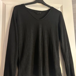 Svart glittrig tröja från ONLY - Säljer en snygg svart glittrig tröja från ONLY i storlek S. Tröjan har en v-ringad hals och långa ärmar. Den är i bra skick. 