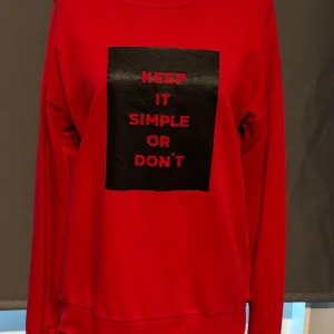 Röd tröja från NA-KD - Säljer en cool röd tröja från NA-KD med texten 'KEEP IT SIMPLE OR DON'T' tryckt i svart och rött på framsidan. Tröjan är långärmad och perfekt för en avslappnad stil. Den är i bra skick och passar perfekt till höst- och vintergarderoben. Skön och bekväm att ha på sig!
