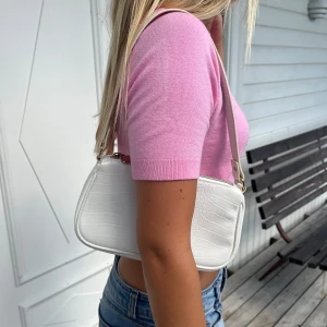 Vit axelväska med krokodilmönster - Säljer en superfin vit axelväska med krokodilmönster. Väskan har en dragkedja upptill och en smal axelrem. Perfekt för både vardag och fest! 🐊✨