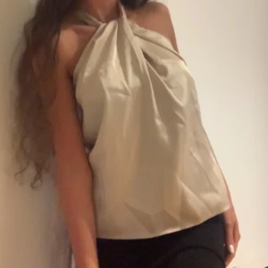 Champagne färgad satin blus / topp med knytning - Helt ny topp som tyvärr är för stor på mig. Bandet runt halsen går att justera beroende på hur högt upp man vill att tröjan sitter
