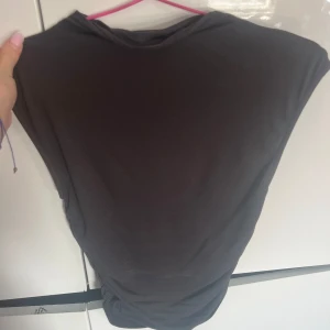 Svart ärmlös topp - Säljer en svart och grå teäja från ginas soft tuch kollektion i storlek XS. Toppen är tight och croppad, perfekt för sommaren eller en utekväll. Den är i bra skick och passar till både jeans och kjol. Materialet är mjukt och stretchigt, vilket gör den bekväm att bära. båda för 50 en för 30