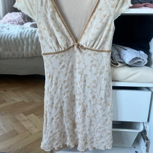 Krämvit och guldig kort klänning - Klänning från Motel Rocks inköpt förra sommaren men endast använd en gång då den är för kort/på gränsen till för kort på mig som är 168cm lång. Storlek S. 