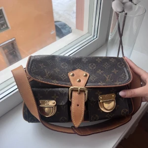 Louis Vuitton Väska  - Jag säljer min älskade ”Hudson cloth handbag”. Den är vintage och köpt på Vestiaire för 14.000kr. Köpte den för ca 3 år sedan, men har inte använt den på 2 år då den bara står och dammar. Den är i bra skick! Skickar gärna fler bilder ❤️ 