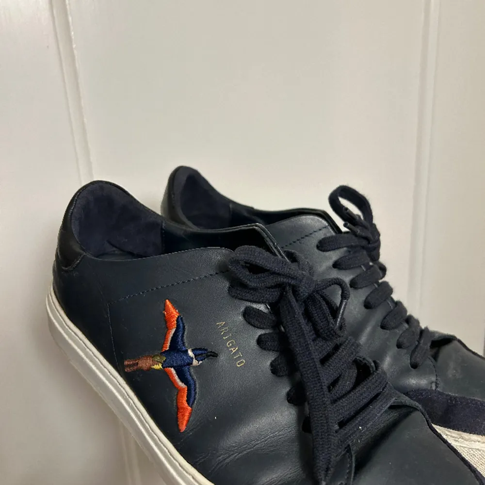 Ett par Arigato Clean 90 Sneaker Navy Leather som är använda vid fåtal tillfällen. Ordinarie pris: 2500kr. Skor.