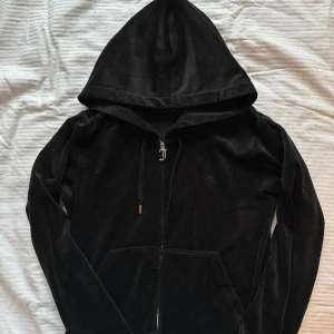 Juicykofta svart  - Fin kofta från Juicy Couture! Bra skick och mjuk! Defekterna syns på bild. Saknar en plupp samt det silvriga har tappat lite färg.