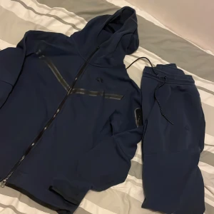 Nike Tech Fleece Dress - Tja säljer denna Nike Tech Fleecen till ett riktigt bra pris!🤙🏼 Skick: 7/10 inga defekter men väl använd och fnottrig. Storlek: M på både byxorna och tröjan. Nypris: 2499 Mitt pris: 549💸 Köpta i Nike butik inne i Mall of Scandinavia. 