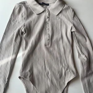 Ljusgrå body med krage och knappar storlek s - Ljusgrå body med krage och knappar. Från Zara i storlek s, endast använd ett fåtal gånger.