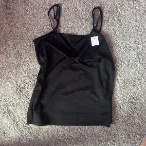 Svart linne - Ett svart linne med smala axelband. Linnet har en enkel och stilren design.