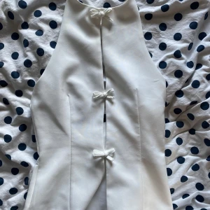 Vit topp - Jättefin vit topp med rosetter. Använd 1 gång och är i ett bra skick. Öppenrygg.   200kr + frakt, använd gärna köp nu ❤️
