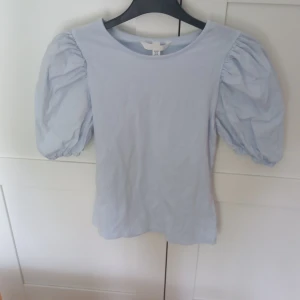 Blå topp med puffärmar  - Säljer en ljusblå topp med puffärmar från H&M i storlek XS. Använd ungefär 5 gånger.