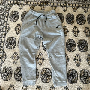 Grå Nike tech byxor - Hej säljer mina grå Nike tech byxor eftersom dom har blivit för små för mig. Köpt för original pris 799kr, de är i topp skick och är i perfekta inför sommaren