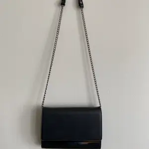 Säljer en svart handväska! Väskan är i gott skick förutom att ena knappen på bandet har lossnat (se bild). Väskan är 20,5cm bred och 14,5cm hög✨