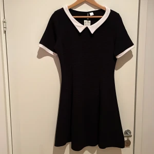 Svart klänning med vit liten krage från H&M - Aldrig använd klänning med prislapp kvar. Liten i storleken.