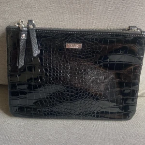 Axelremsväska i croco  - Axelremsväska i lackad croco från Don Donna. Aldrig använd. Mått: bredd 23cm, höjd 17cm, djup 3cm