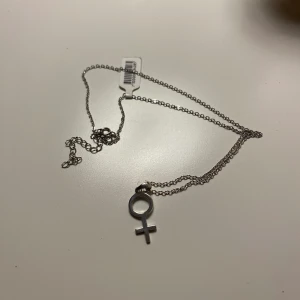 Halsband  - Oanvänt halsband med kvinnotecken. Tror det är av silver men är osäker
