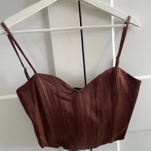 Brun kort topp - Superfin, oanvänd brun lite glansig topp från Zara! Strl M men liten i storleken.
