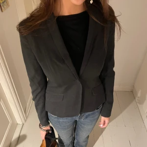 GRÅ FIGURSYDD KAVAJ - Grå figursydd kavaj från fint märke, perfekt till festligare tilfällen! Modell 175 cm. Storlek 38 men sitter mer som en 36/S💋 Hör av er vid frågor/fler bilder