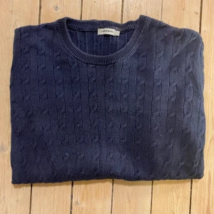 J.Lindeberg stickad kofta - Säljer den har riktigt feta koftan perfekt för vinterkylan och de som gillar Stockholmsstil👍💯 koftan är i mörkblå färg och storlek l
