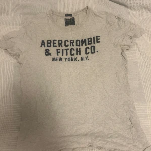 Abercrombie & fitch T-shirt  - En vit/grå T-shirt från Abercrombie i storlek M. Bra skick och skönt material 