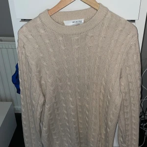 Beige kabelstickadtröja - Beige kabelstickad tröja från Selected Homme. Mycket bra skick använd fåtalet gånger, 1-3 gånger. Passar perfekt på en sommarkväll