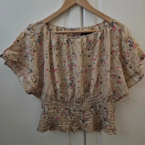 Blus nyskick zoul - Söt blus med blommigt mönster och knappar baktill. Blusen har en elastisk resår nedtill och korta puffärmar. Strl 40 men är mer som en strl 36-38. Katt finns I hemmet