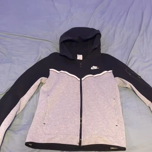 Nike tech fleece grå och svart - Säljer denna fina tech fleece som är köpt från nike hemsida. Hoodien är nästan i top skick då den inte har tappat någon färg eller inte har några hål. Skick 9/10 storlek S.