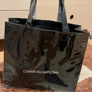 Comme Des Garcons Tote -  !!Worn only once as emergency carry on in Japan. Therefore like brand new!! Kraft Paper Interior. Inner Cotton Fabric Lining. Printed Silver Branding at Front and Back.  39cm length x 12.5cm widght x 34cm lenght 