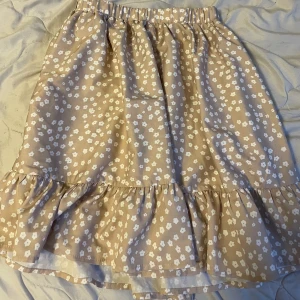 Blommig kjol - En väldigt enkel beigeaktig blommig kjol i storlek 160.