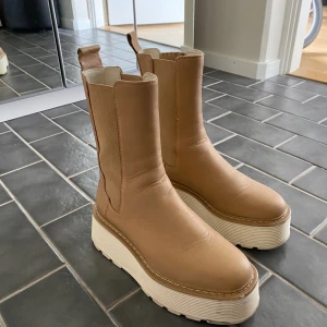 Beige boots med platå - Tillverkade i läder. Sparsamt använda. Lite mörka nötmärken som att vänta av ljusa skor men jag har underhållit skorna med både läderbalsam och impregnering.