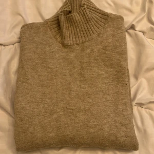 Stickad tröja  - Säljer en beige stickad tröja från vila med en liten polokrage, endast använd ett fåtal gånger 