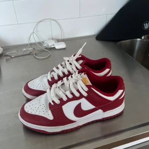 Nike dunk  - Ett par röda Nike dunk köpt för nypris 2 500 kr. I storlek 40,5. Använt ett par gånger, sulan är lite smutsig och snörerna har någon fläck men annars i bra skick. Inget kvitto eller låda kvar men dem är äkta. Pris kan diskuteras vid snabb affär. 