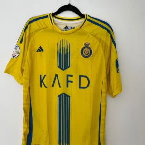 Al Nassr 2024/25 hemmatröja - Ronaldo  - Skick: helt nytt och oanvänd  Storlek: M Tröjan finns i Stockholm/Vallentuna men frakt erbjuds via postnord (2-3 dagar)  Skriv till mig ifall ni har en fråga.