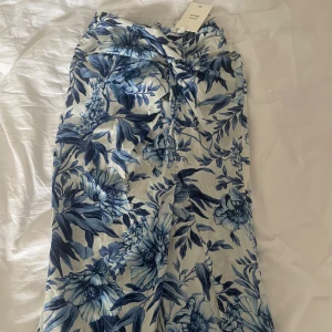 Blå vit linne kjol - En aldrig använd vit och blå blommig linne kjol från h&m. Säljer då det är fel storlek.