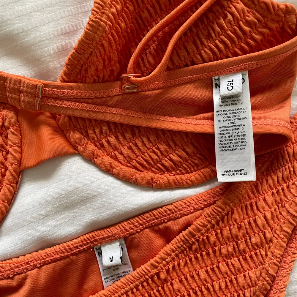 Bikini set i burnt orange färg, toppen har volangliknande stil på banden. Toppen 75 d och underdelen storlek m. Övrigt.