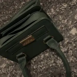En liten grön väska med både långa och korta band, är jätte fin och inte alls använd. Har guld detaljer på Säljer denna för 75kr plus frakt 