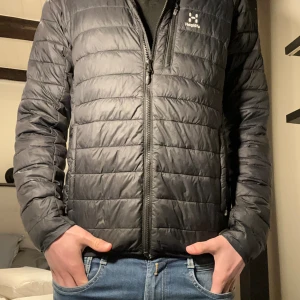 Haglöfs jacka  - Tunn Svart Haglöfs dun jacka. Två små hål vid vänstra ärmen annars inga skador men hålen är inget som syns när man bär jackan. Nypris ca 2900kr på zalando 