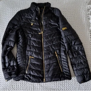 Barbour  - Den är möjligen använd en gång.   Svart med gulddetaljer. (Snyggast)  Superfin, fantastiskt snygg variant med hur panelerna är sydda.  Välarbetad, dekorativa detaljer.  Klassisk tidlös modell, passar till allt.  SIZE: 36/38 (S), true to size