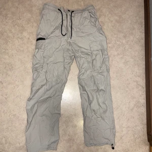 Grå/vita cargo byxor - Feta cargo byxor från HM. Nästan material som parachute pants. Svarar på alla frågor.