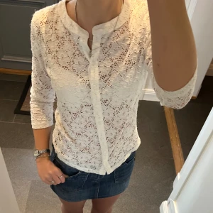 Vit spetströja  - Vit kofta i spets med blommönster från Indiska. Storlek M. Fint skick förutom lite lösa trådar på inre sidan av ärmarna (sista bilden). Använd gärna köp nu!