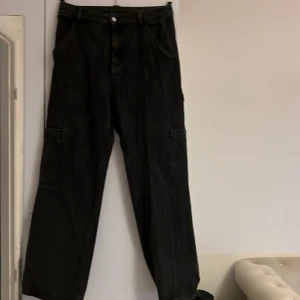 Stentvättade cargojeans - Fickor fram och bak. Och fickor som tillkommer vid cargomodellen. Något slitna i bak längst ner på benen då dom varit för långa när jag gått i dom 