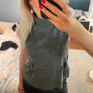 Stickad topp - Mörkgrå stickad kortärmad topp med band i midjan för att knyta. Jättebra skick!