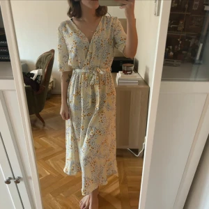 Vit blommig omlottklänning - Resår i midjan, helt ny. Köper du med instabox skickar jag samma dag🫶🏻