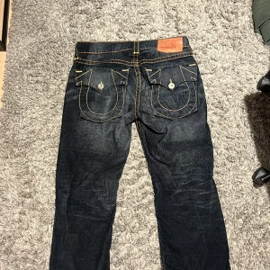 True Religion byxor  - Snygga svarta True Religion jeans med perfekt fade. Jeans är hyfsat baggy. Jag kan inte upptäcka några slitningar på dem trots att jag och ägaren innan mig använt byxorna väl